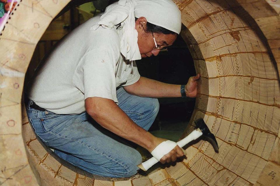 Mark Miyoshi sits inside a barrel, carving it to improve its resonance